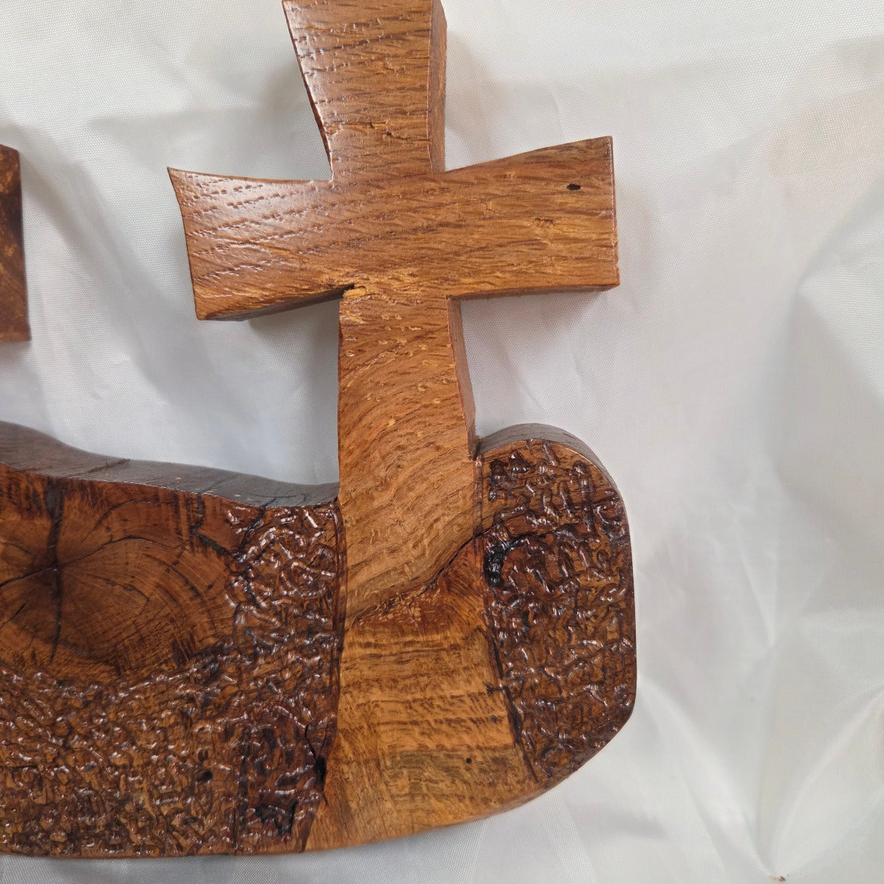 A white oak decorative wall plaque featuring three stylized Christian crosses cut from a single slab, hand carved with dark brown wooden base, 