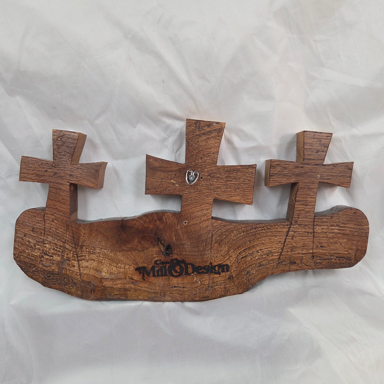 A white oak decorative wall plaque featuring three stylized Christian crosses cut from a single slab, hand carved with dark brown wooden base, 
