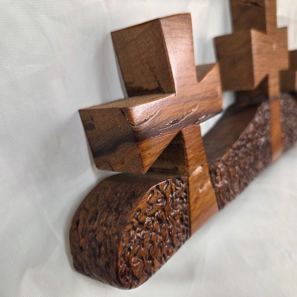 A white oak decorative wall plaque featuring three stylized Christian crosses cut from a single slab, hand carved with dark brown wooden base, 