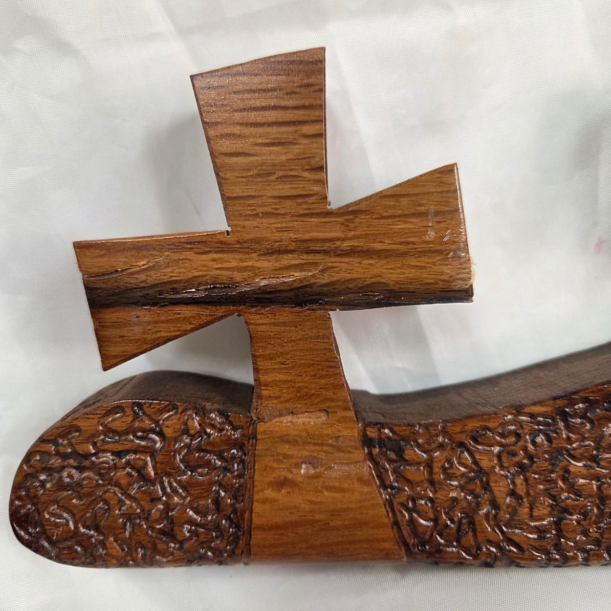 A white oak decorative wall plaque featuring three stylized Christian crosses cut from a single slab, hand carved with dark brown wooden base, 