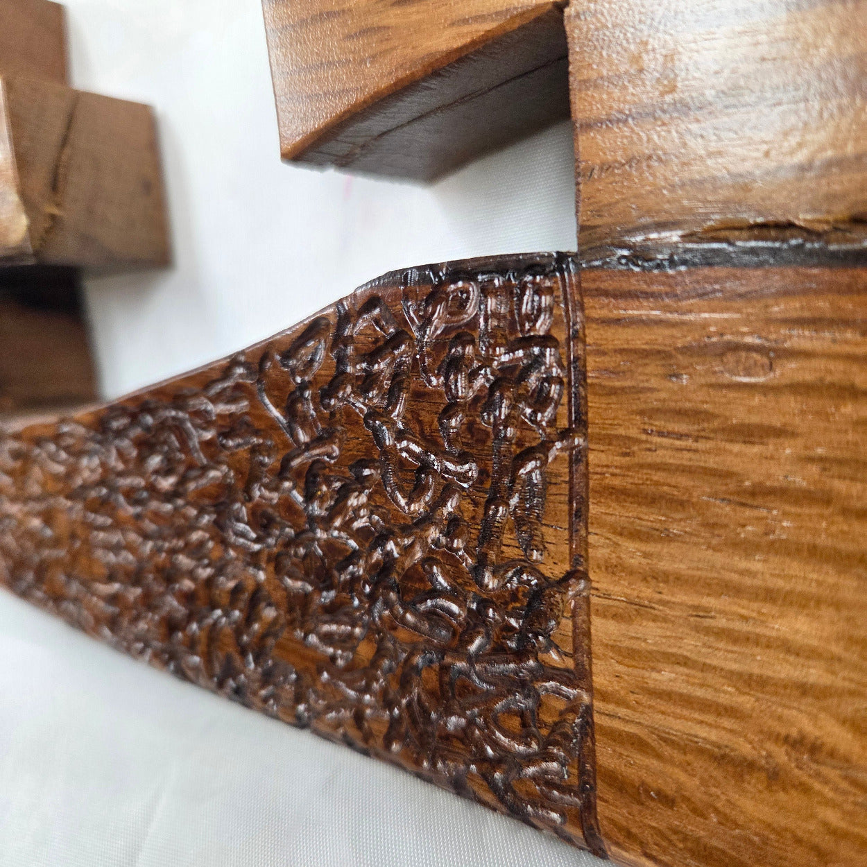 A white oak decorative wall plaque featuring three stylized Christian crosses cut from a single slab, hand carved with dark brown wooden base, 