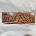 A rectangular white oak sign with a natural brown wood grain finish, featuring the word 'HOWDY' cut out in blue epoxy outline lettering, 