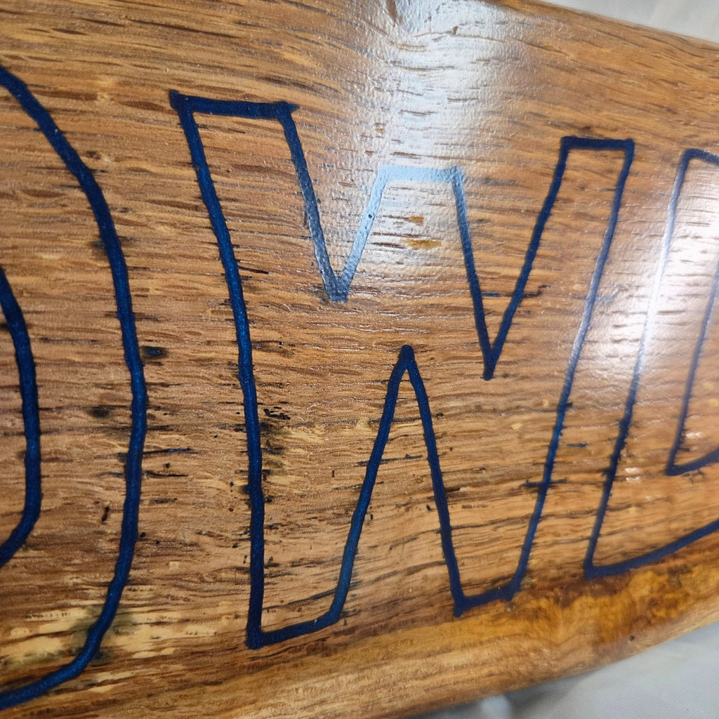 close up A rectangular white oak sign with a natural brown wood grain finish, featuring the word 'HOWDY' cut out in blue epoxy outline lettering, 