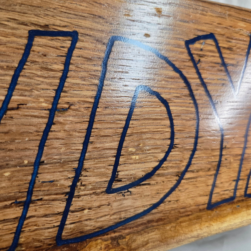 close up A rectangular white oak sign with a natural brown wood grain finish, featuring the word 'HOWDY' cut out in blue epoxy outline lettering, 