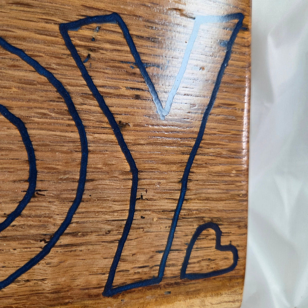 close up A rectangular white oak sign with a natural brown wood grain finish, featuring the word 'HOWDY' cut out in blue epoxy outline lettering, 