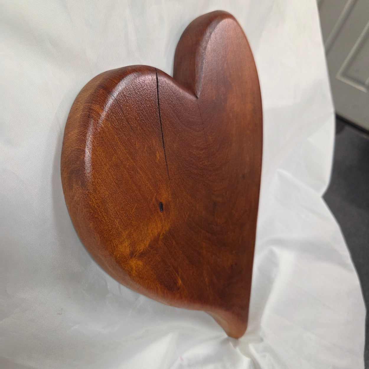 A heart-shaped mesquite wall art with a polished finish, showcasing natural wood grain