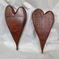A pair of heart-shaped mesquite wall art with a polished finish, showcasing natural wood grain