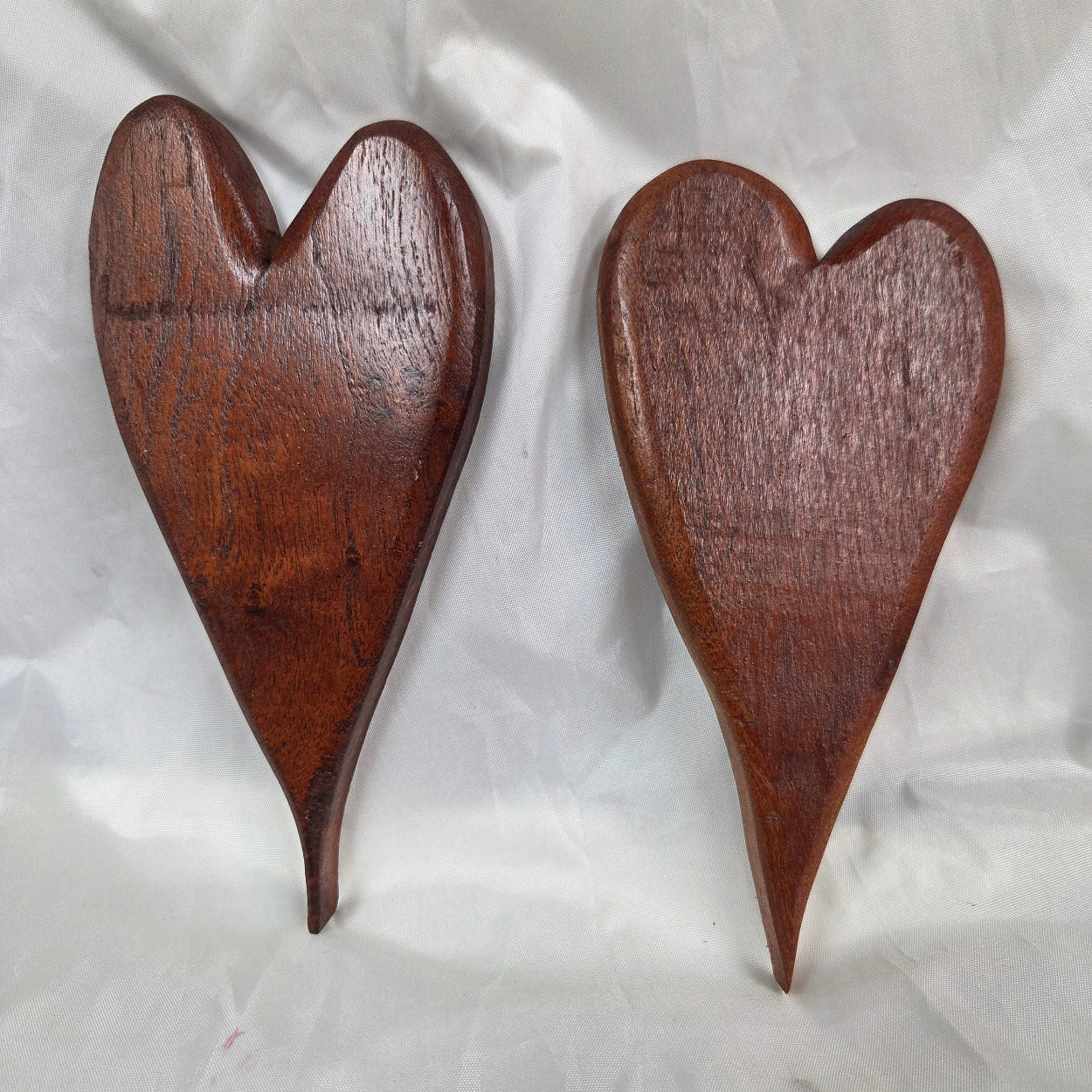 A pair of heart-shaped mesquite wall art with a polished finish, showcasing natural wood grain
