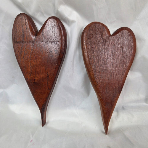 A pair of heart-shaped mesquite wall art with a polished finish, showcasing natural wood grain