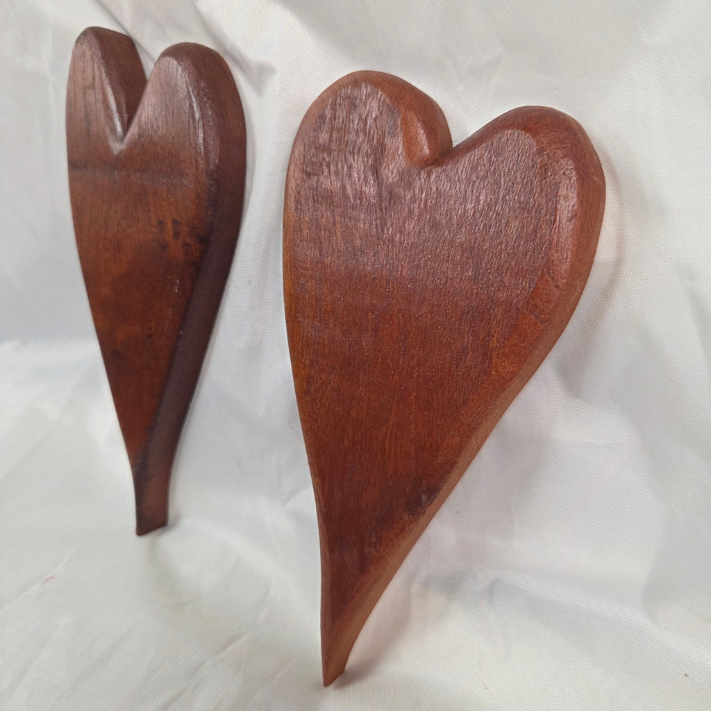 A pair of heart-shaped mesquite wall art with a polished finish, showcasing natural wood grain
