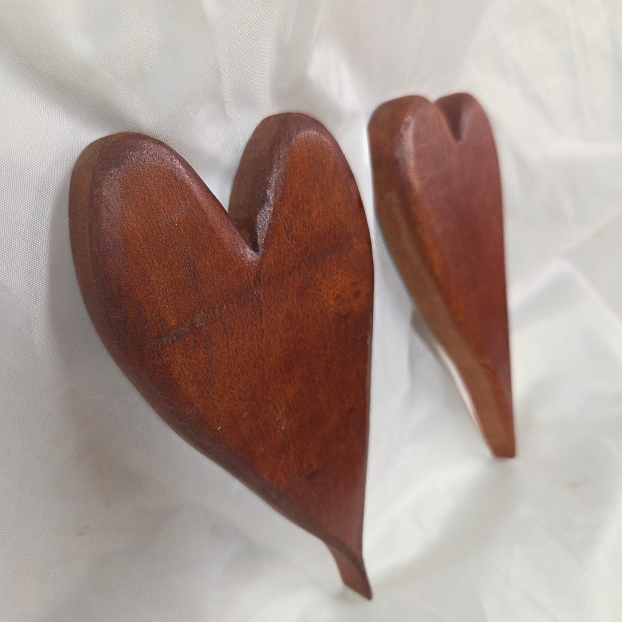 A pair of heart-shaped mesquite wall art with a polished finish, showcasing natural wood grain