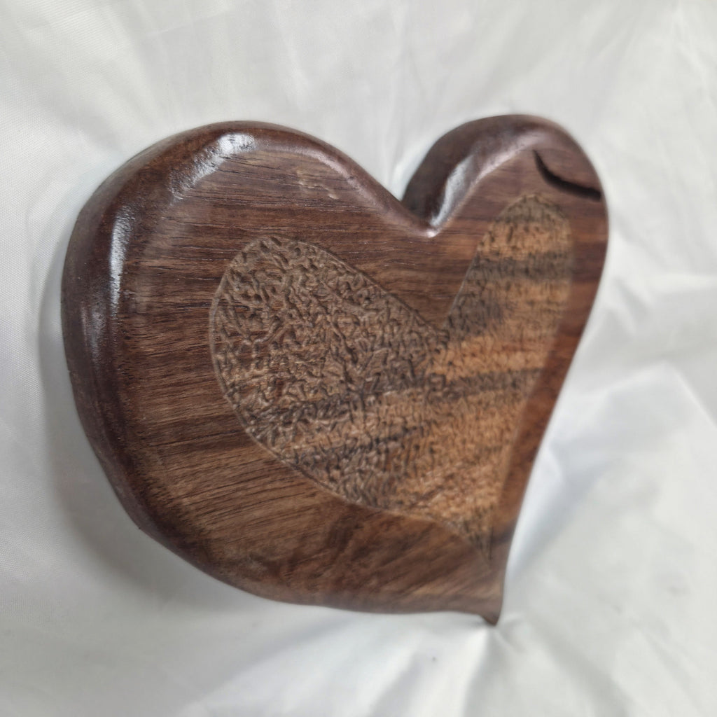 A hand carved heart-shaped White Oak Hanging heart wall art with a carved pattern in the center, photographed on a wrinkled white background.