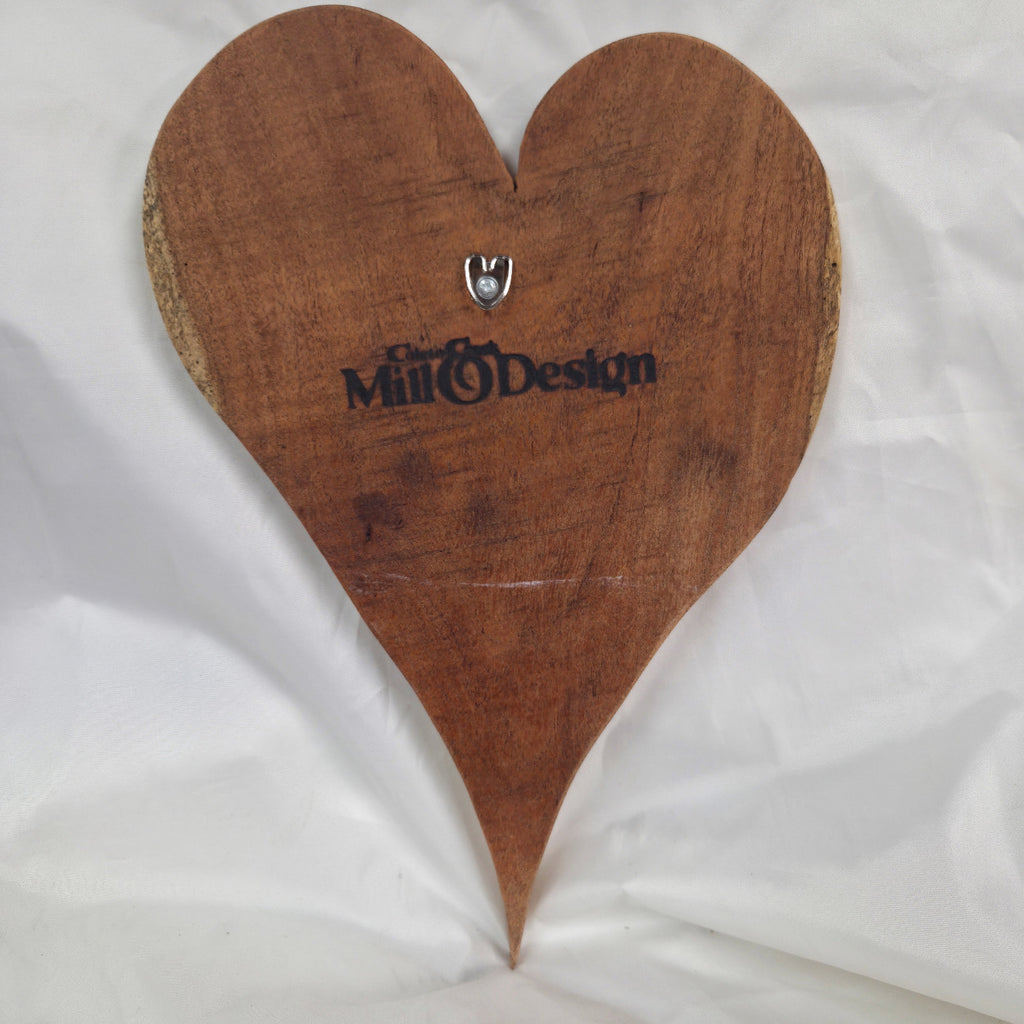 A heart-shaped wooden plaque with a rustic finish, featuring the 'Coleto Crekk Mill & Design' logo and a small silver metal hook at the top center, displayed on a wrinkled white fabric background.
