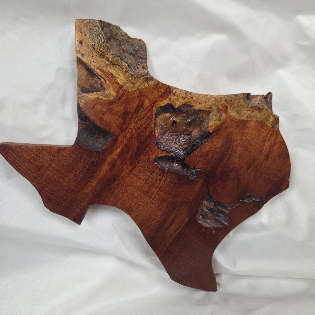 A rustic Texas-shaped wall art plaque made from mesquite wood with a dark, textured natural with natural deformities