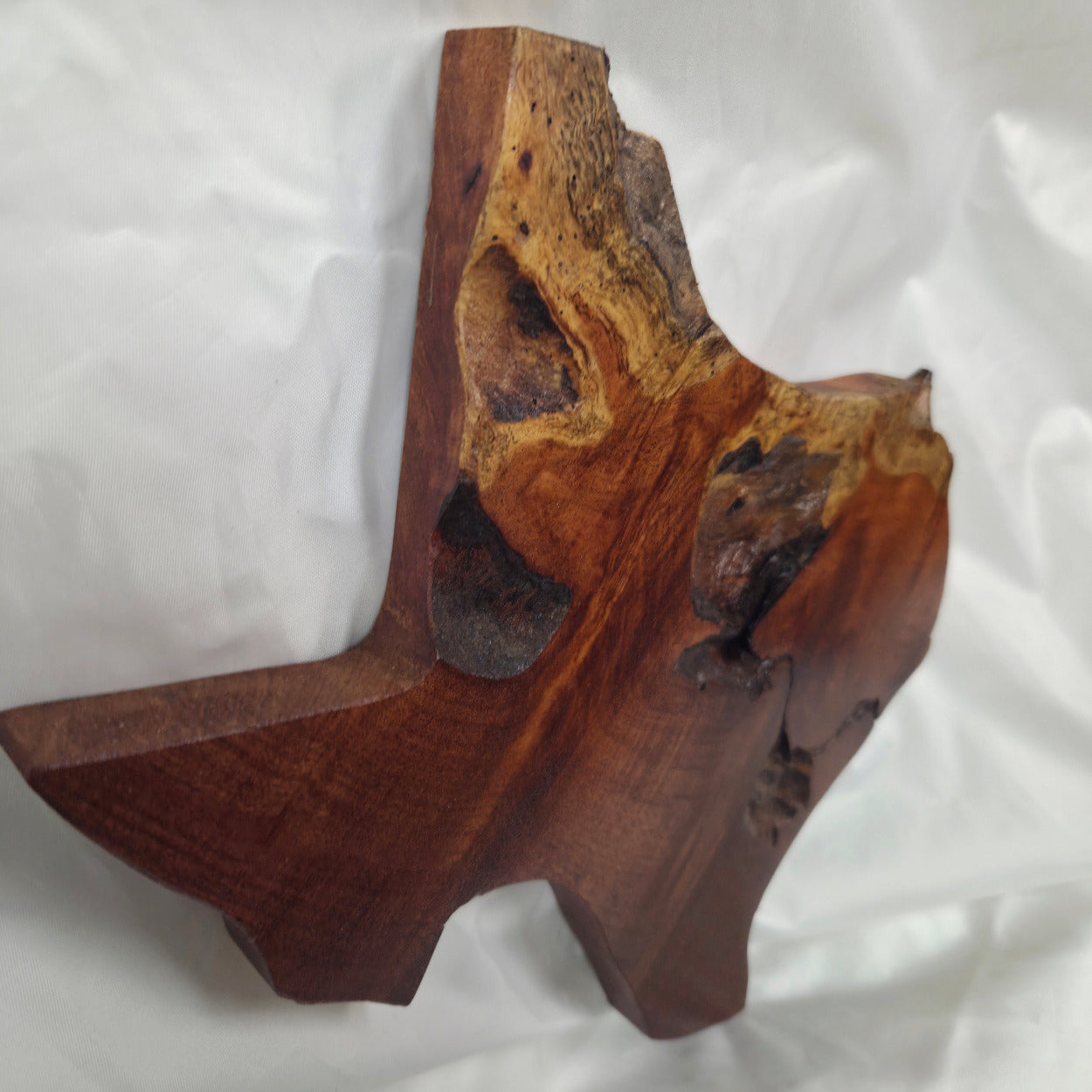 A rustic Texas-shaped wall art plaque made from mesquite wood with a dark, textured natural with natural deformities