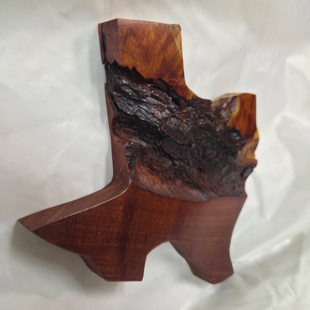 close up A rustic Texas-shaped wall art plaque made from mesquite wood with a dark, textured natural bark-like band running diagonally across the center, 