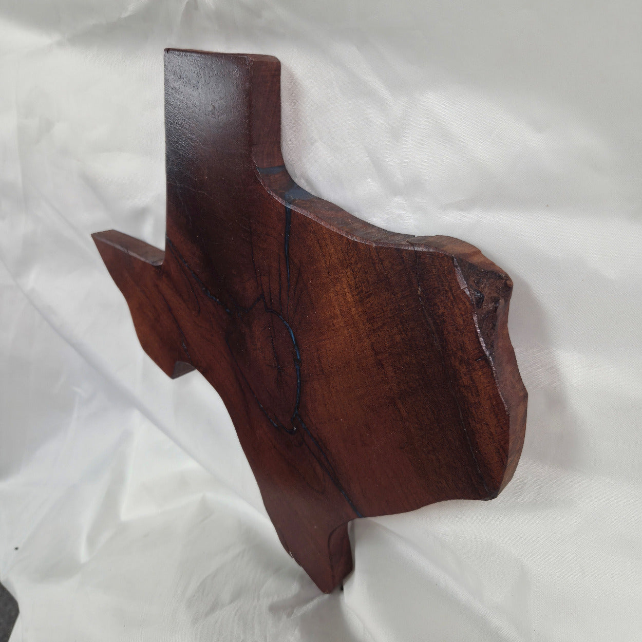 A rustic, hand-shaped wooden plaque wall art in the shape of Texas, made from mesquite wood with natural grain, dark burn marks and blue epoxy fill