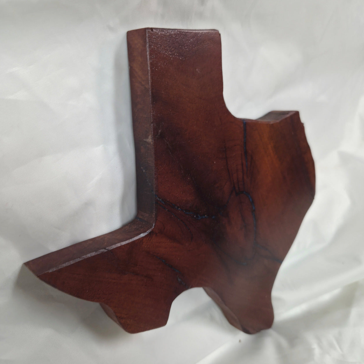 A rustic, hand-shaped wooden plaque wall art in the shape of Texas, made from mesquite wood with natural grain, dark burn marks and blue epoxy fill