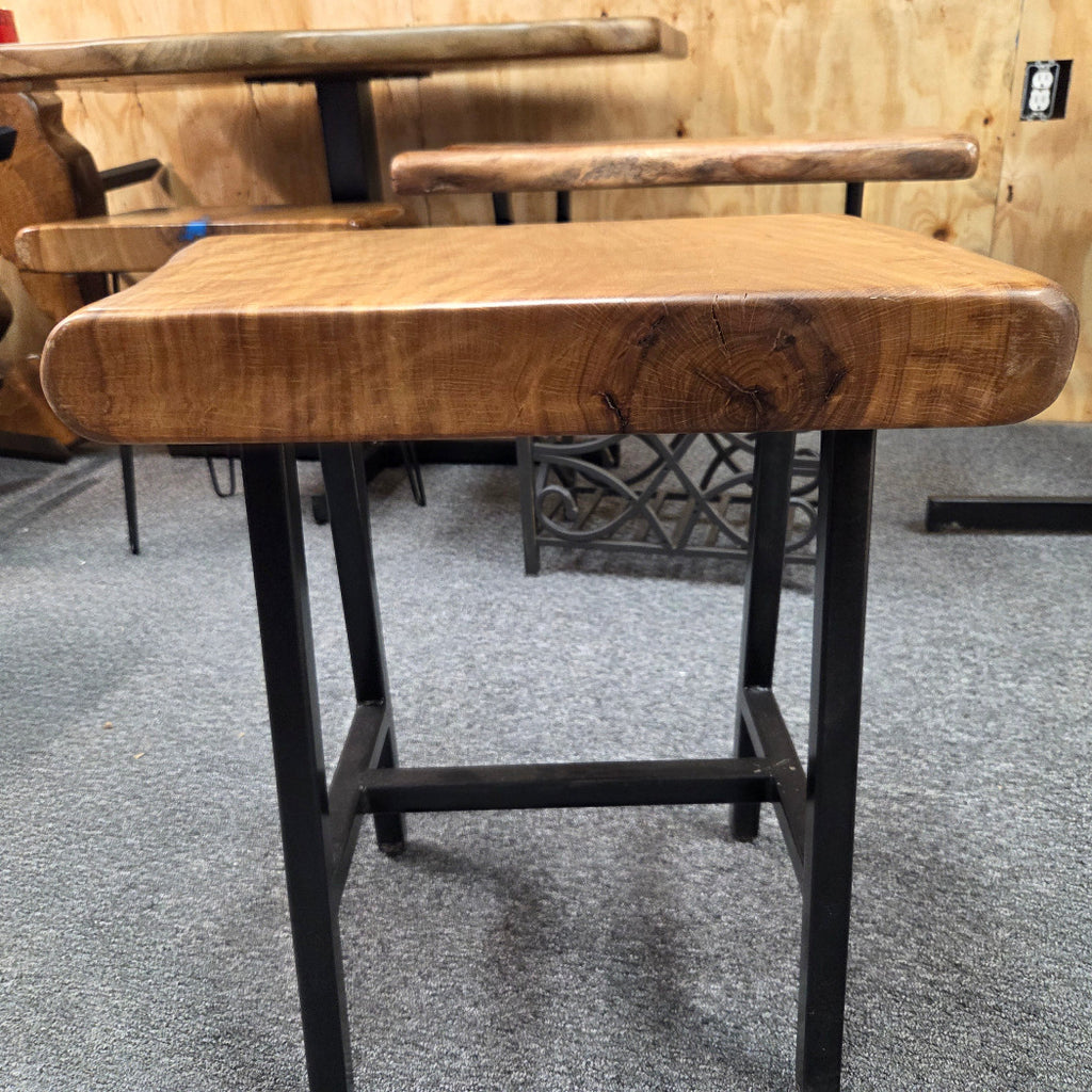 A rustic Live Oak end table with a thick, live-edge natural wood seat and a black metal frame, set on a gray carpeted floor.