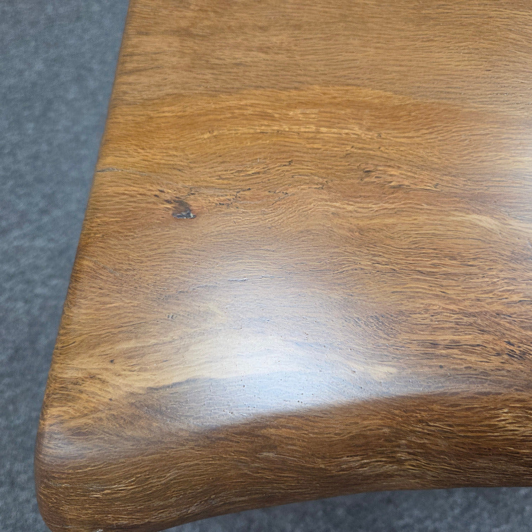 close up A square Live Oak end table with a live-edge natural top and black metal legs, furniture showroom setting on a gray carpet.