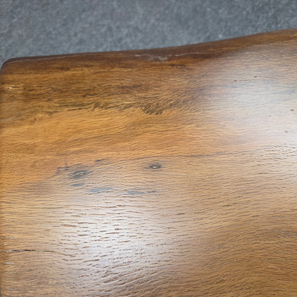 close up A square Live Oak end table with a live-edge natural top and black metal legs, furniture showroom setting on a gray carpet.