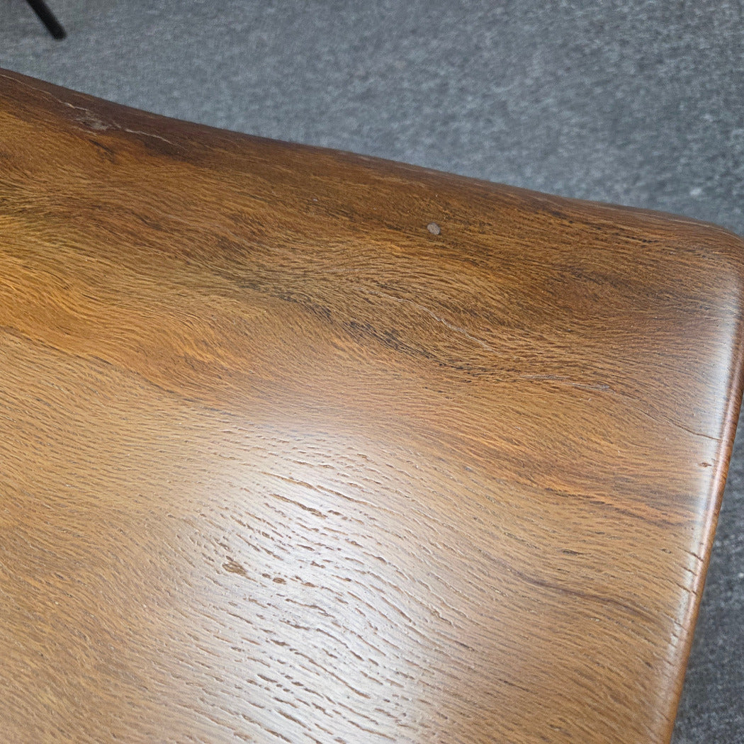 A square Live Oak end table with a live-edge natural top and black metal legs, furniture showroom setting on a gray carpet.