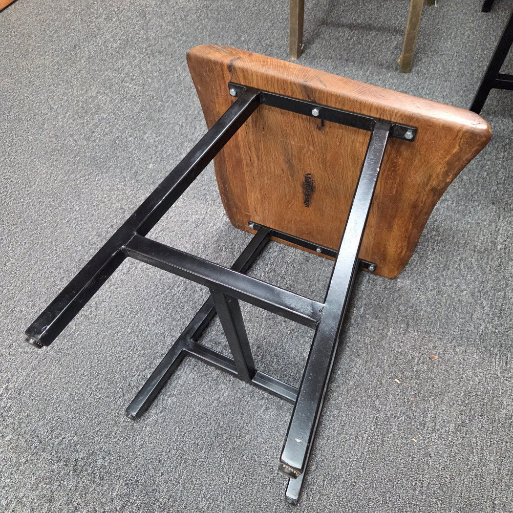 bottom view A square Live Oak end table with a live-edge natural top and black metal legs, furniture showroom setting on a gray carpet.