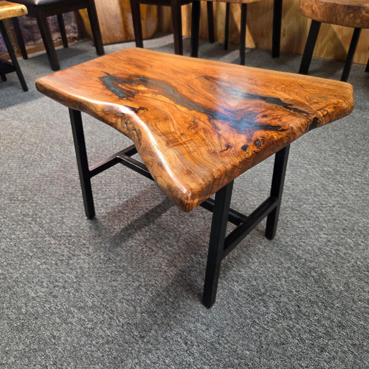 Handcrafted live edge wood table with black epoxy-filled voids and custom black metal base