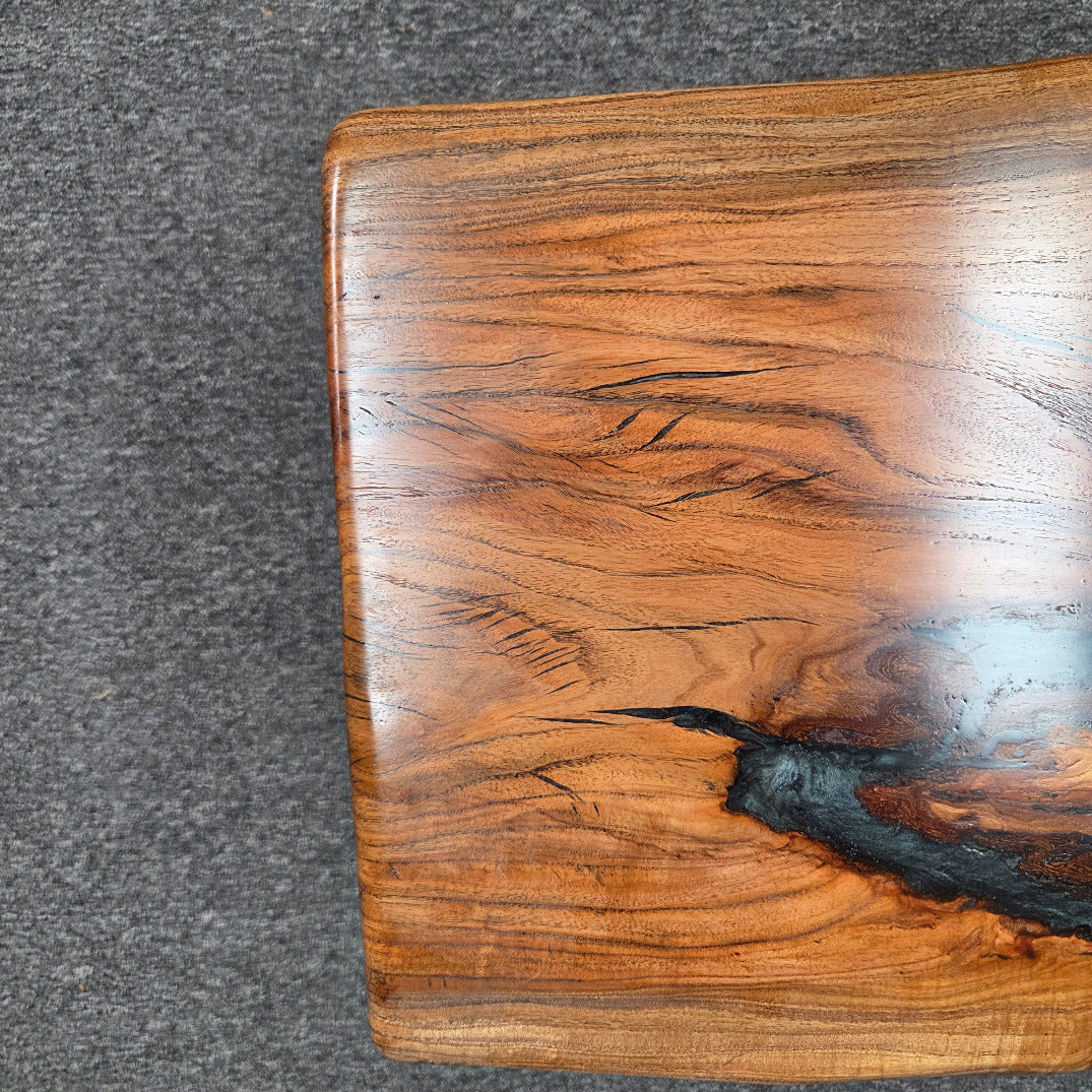 Handcrafted live edge wood table with black epoxy-filled voids and custom black metal base