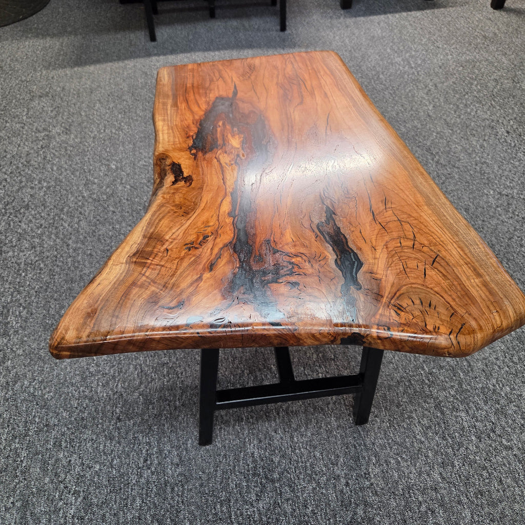 Handcrafted live edge wood table with black epoxy-filled voids and custom black metal base