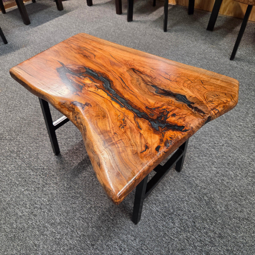 Handcrafted live edge wood table with black epoxy-filled voids and custom black metal base