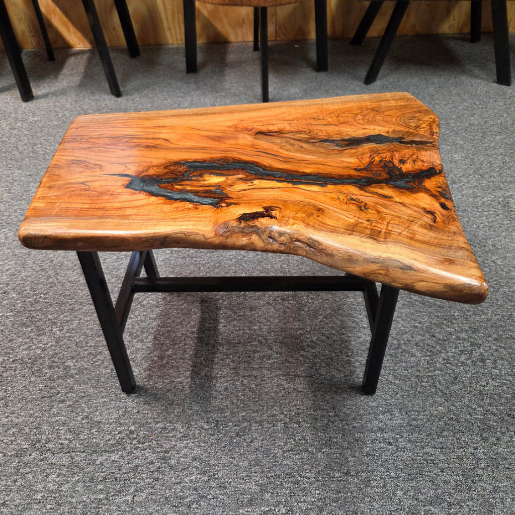 Handcrafted live edge wood table with black epoxy-filled voids and custom black metal base
