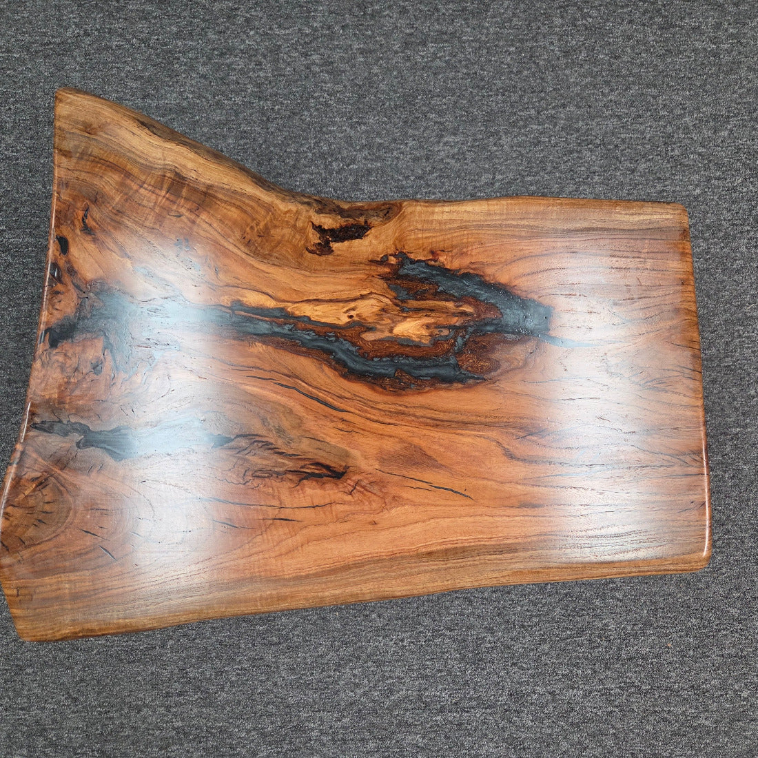Handcrafted live edge wood table with black epoxy-filled voids and custom black metal base
