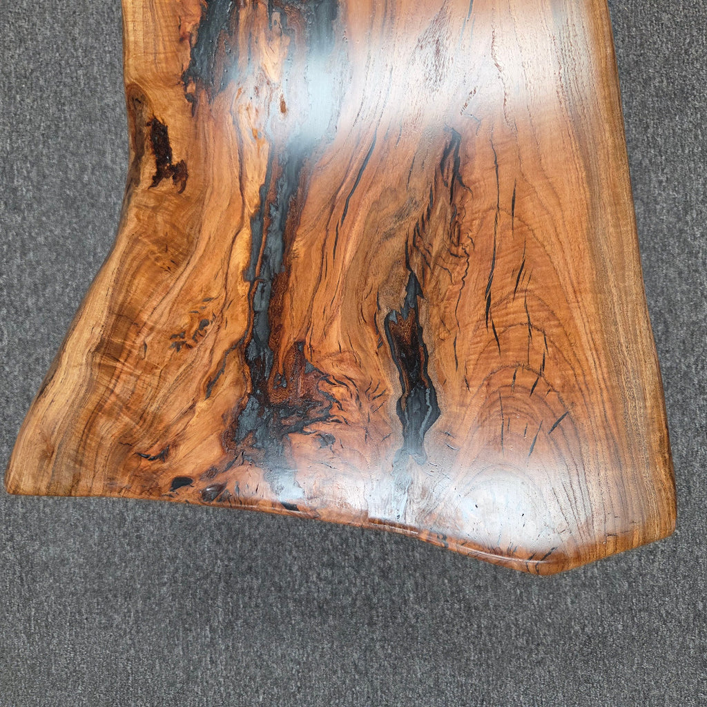Handcrafted live edge wood table with black epoxy-filled voids and custom black metal base