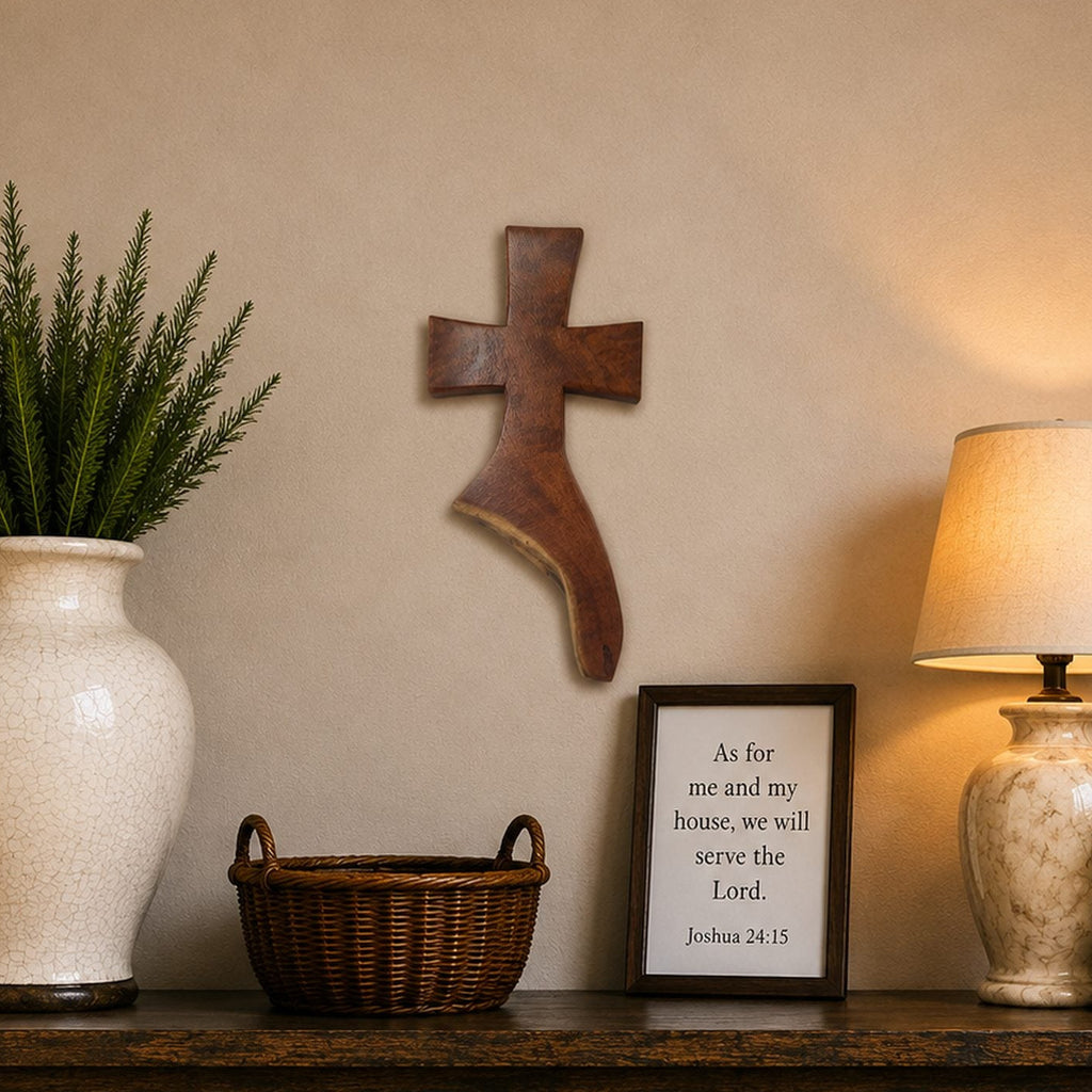 A styled interior scene showing a dark wood console table against a beige wall, with a large white vase holding a green plant on the left, a small wicker basket in the center, a framed scripture print, and a lit table lamp on the right.